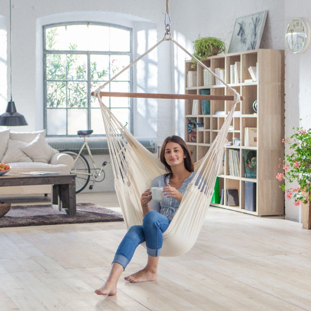 Jeunne femme dans une chaise hamac colombienne buvant du thé dans son salon